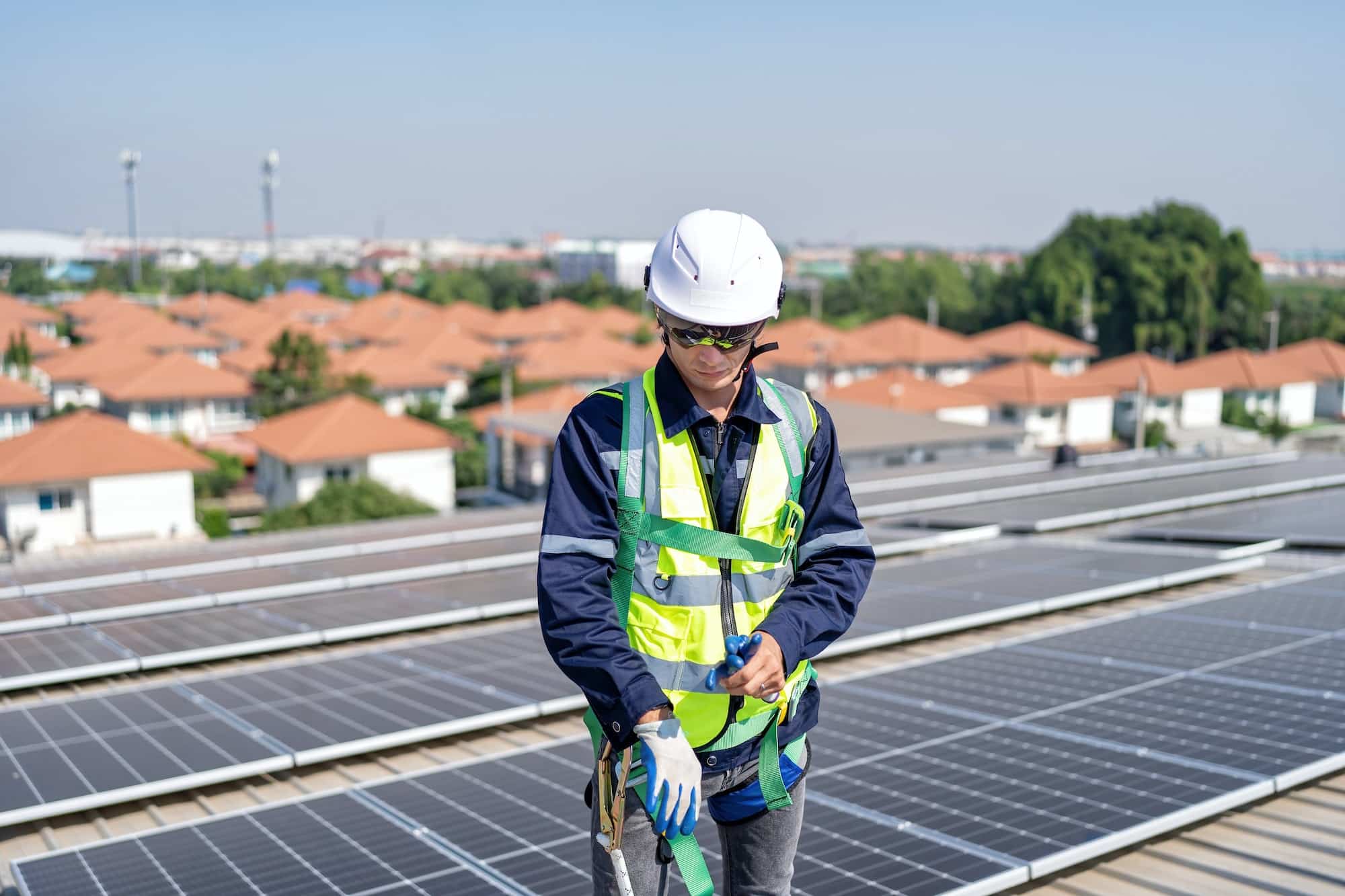 Engineer on rooftop stand next to solar panels wear safety gear wear hand gloves ready to work