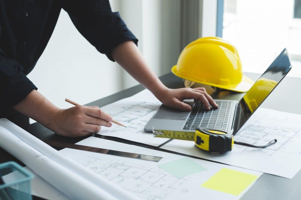 Architects or engineers working construction and drawing construction plans, printing, writing